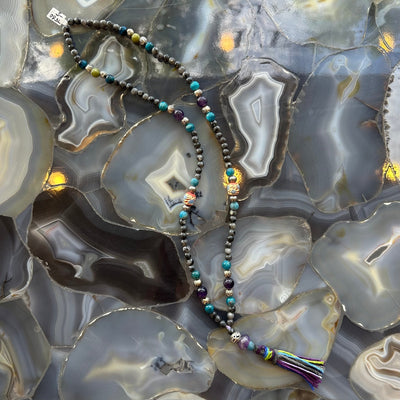 Close-up view of Larvikite Mala with mixed stone beads on a neutral surface