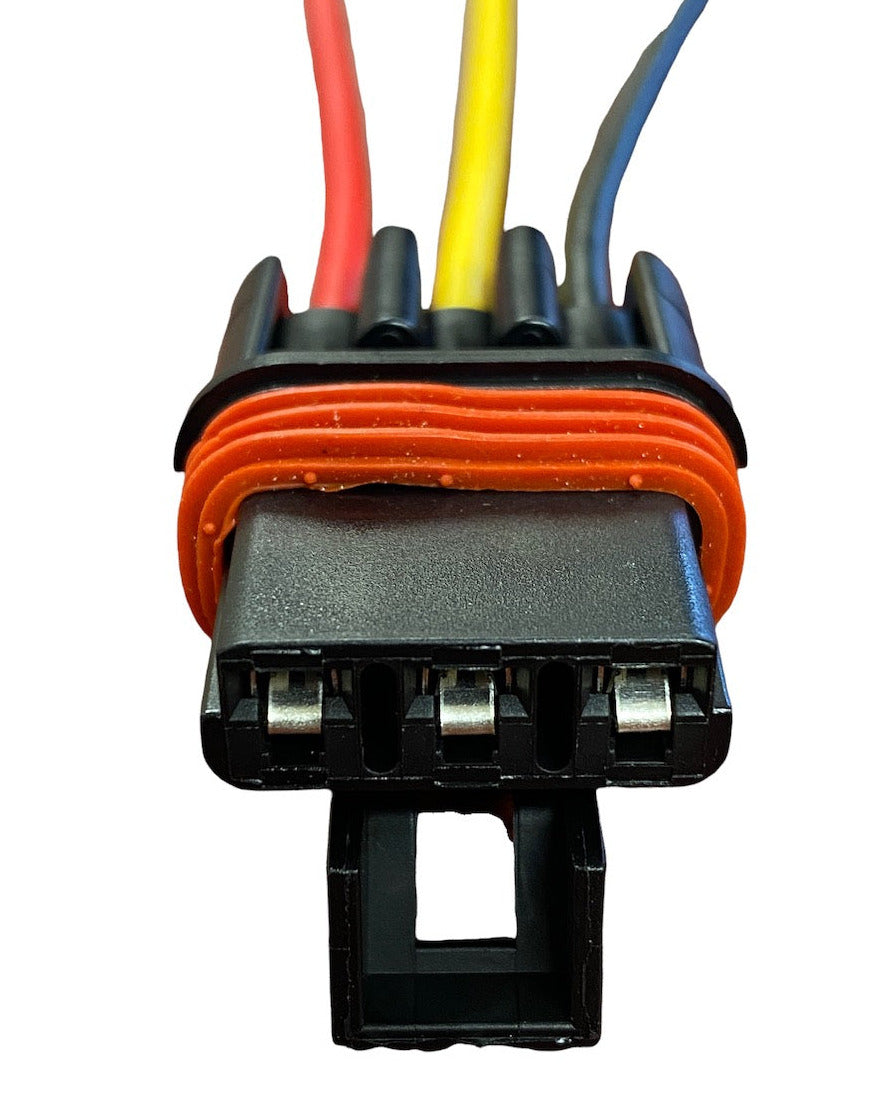 Close-up of a black rectangular electrical connector with red, yellow, and blue wires, sealed by an orange rubber gasket visible around the base.