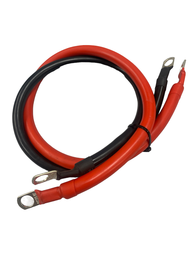 Coiled battery jump cables with red and black insulation and metal ring terminal connectors at both ends on a white background.