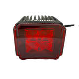 Compact black LED pod light with prominent cooling fins and a transparent red lens cover showing four internal LEDs arranged in a square pattern.