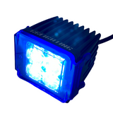 Compact black LED pod light with bright blue illuminated lens and ribbed heat sink housing, viewed at a slight angle showing front and top sides.