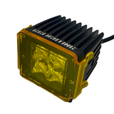 Compact black LED pod light with pronounced cooling fins and a yellow transparent lens cover secured by four corner clips, shown at a slight angle.