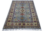 Rectangular Afghani Kazak wool rug with blue field and multi-colored geometric medallions, surrounded by cream and blue patterned borders with fringed edges.