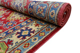 Rolled hand-knotted Afghani Kazak wool rug with geometric patterns in red, blue, cream, and green tones, showing detailed border and central motifs.
