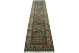 Long, narrow Afghani Kazak wool runner rug with a green central field featuring large geometric medallions and multicolored intricate borders, finished with fringed ends.