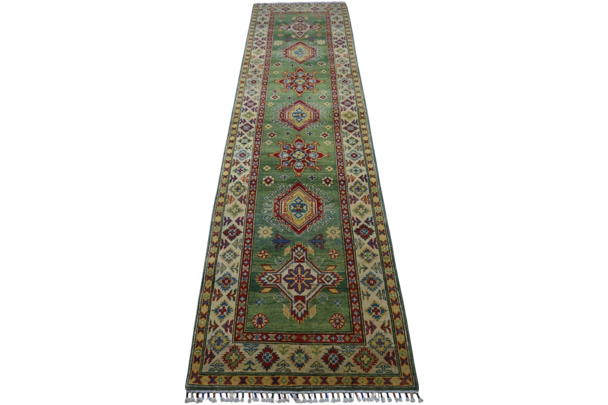 Long, narrow Afghani Kazak wool runner rug with a green central field featuring large geometric medallions and multicolored intricate borders, finished with fringed ends.