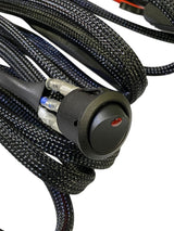 Close-up of black woven braided wiring harness with a round black rocker switch featuring a small red indicator light.