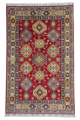 Hand-knotted Afghani Kazak wool rug in red with intricate geometric patterns, laid on wooden floor