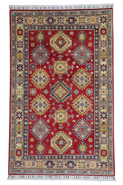Hand-knotted Afghani Kazak wool rug in red with intricate geometric patterns, laid on wooden floor