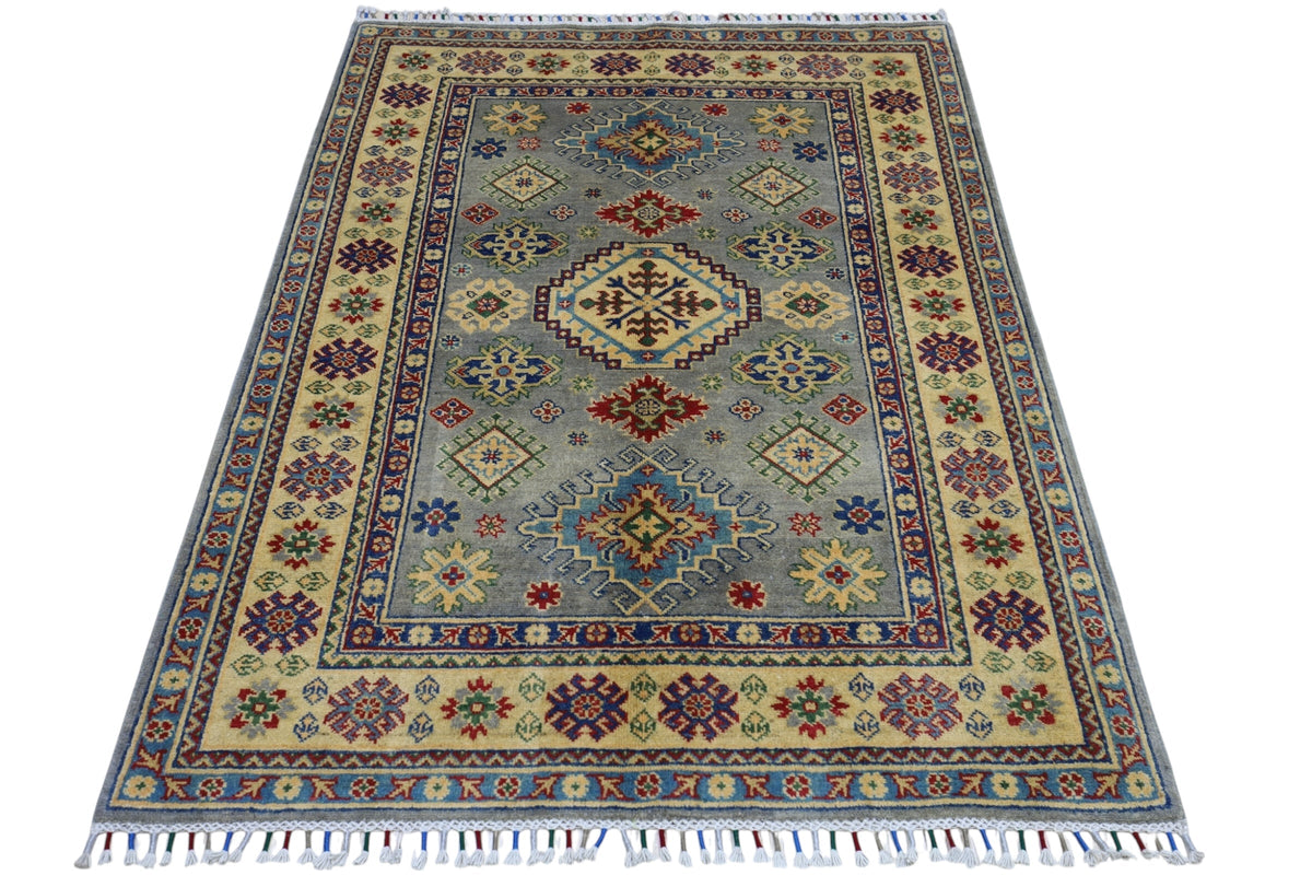 Hand-knotted Afghani Kazak wool rug with muted blue center, intricate multicolor geometric patterns, and cream border with floral motifs and fringed ends.
