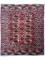Rectangular vintage Turkoman Tekke rug featuring repeating symmetrical medallion motifs in rust, beige, and dark blue on a brick-red field with patterned borders.