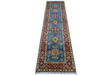 Long, narrow Afghani Kazak wool rug with a blue central field featuring geometric medallions in red, yellow, and white, framed by intricate red and beige borders with floral patterns.