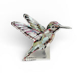Hummingbird Acrylic Tabletop Art displayed on a wooden desk with a vintage book and green plant
