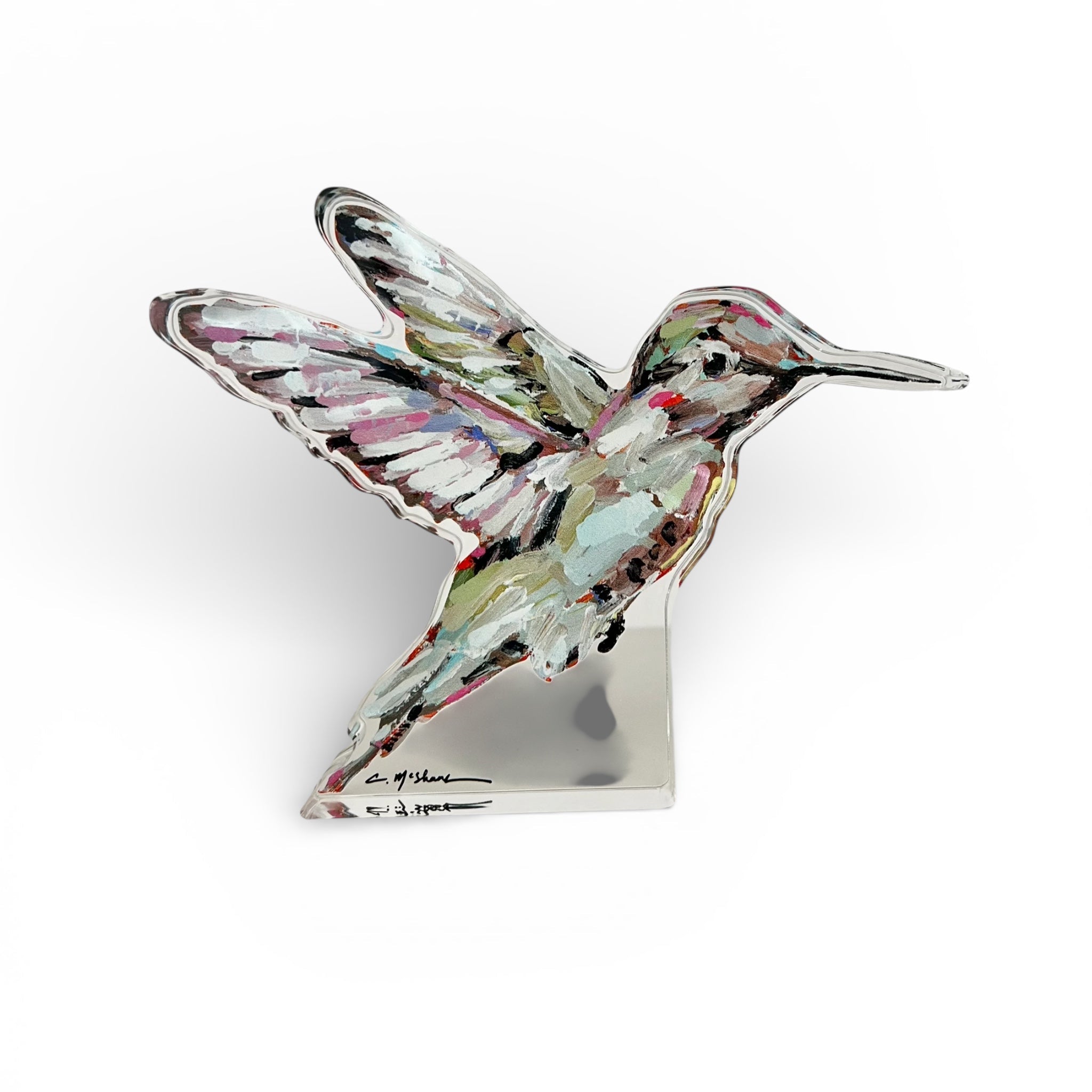 Hummingbird Acrylic Tabletop Art displayed on a wooden desk with a vintage book and green plant