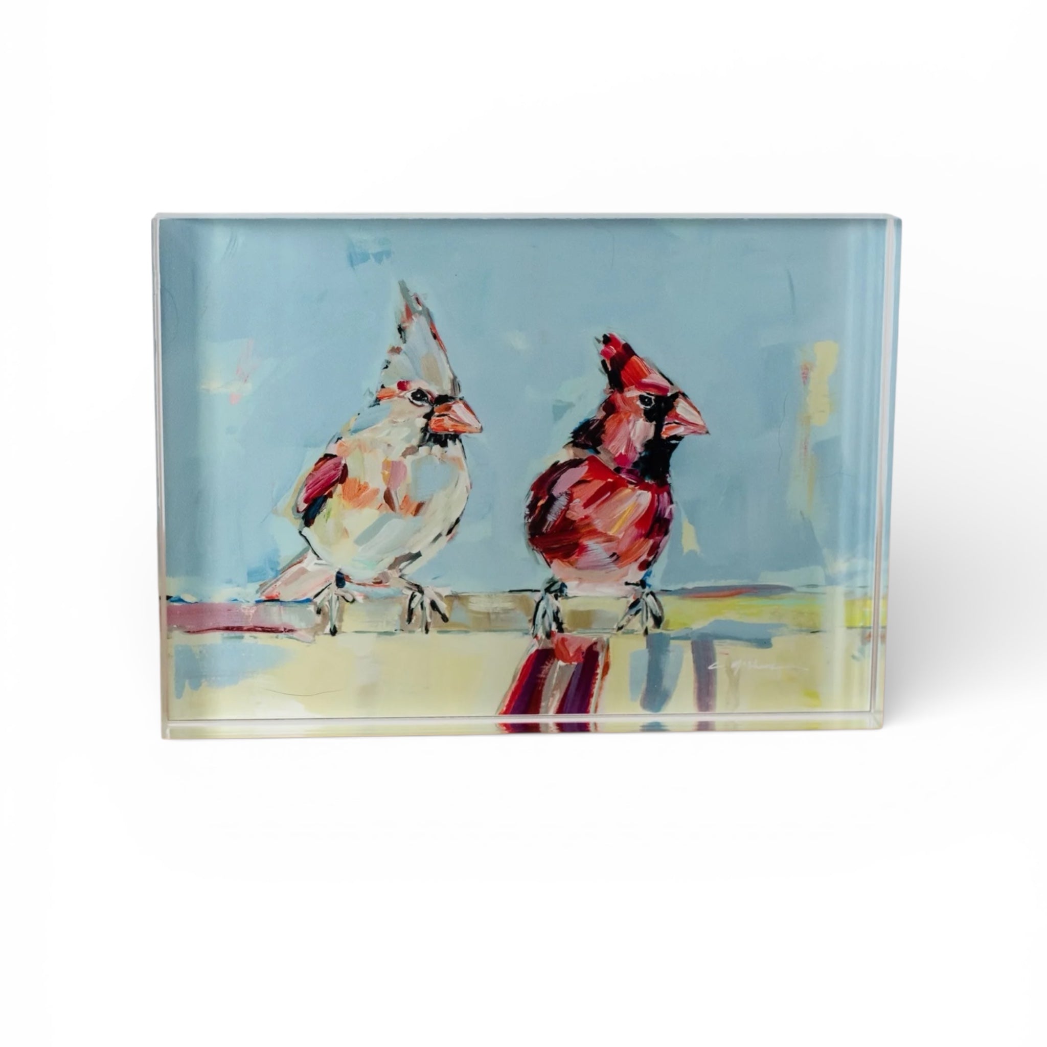 Freestanding acrylic block art displaying a red cardinal figured on a white background with natural wooden table surface