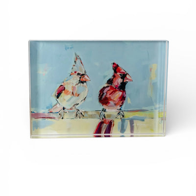 Freestanding acrylic block art displaying a red cardinal figured on a white background with natural wooden table surface