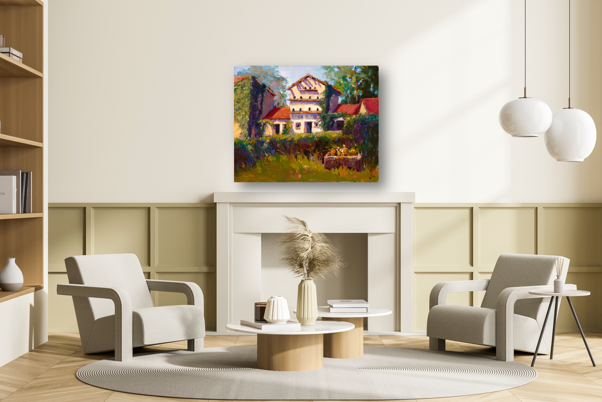 Contemporary living room with two light gray armchairs and a circular rug in front of a white fireplace topped with a colorful canvas painting of a house surrounded by greenery.