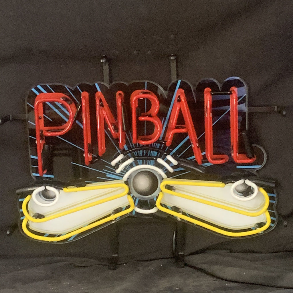 Neon sign spelling 'PINBALL' in red letters with a blue and black striped background and yellow and white pinball flippers below the text on a dark backdrop.