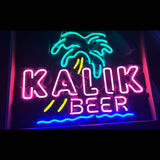 Neon sign with teal palm tree and pink letters spelling 'KALIK' above yellow accents and pink 'BEER' with blue wave line below on dark background