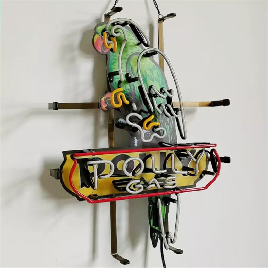 Neon sign shaped like a green parrot perched above a yellow and red banner reading 'Polly Gas' in white neon letters, mounted on a white wall.
