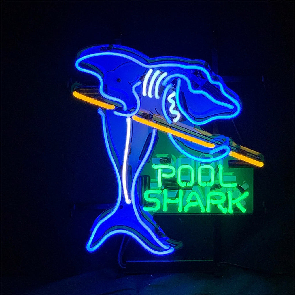 Neon sign depicting a blue shark holding a yellow pool cue with green text reading 'POOL SHARK' beneath it on a black background.