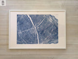 Framed 24x36 art print showing detailed blue tree rings and cracks of a locust cross-section, mounted on a pale wooden floor background.