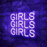 Purple neon sign displaying the word GIRLS repeated three times in stacked alignment, mounted on a dark brick wall with a chain hanger.