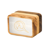 Three Qi-Me devices in Olive, Pine, and Walnut wood finishes displayed side by side on a white surface