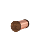 Cylindrical copper Qi-Shield device with dark wood end cap engraved with a shield logo and text, shown on a white background.