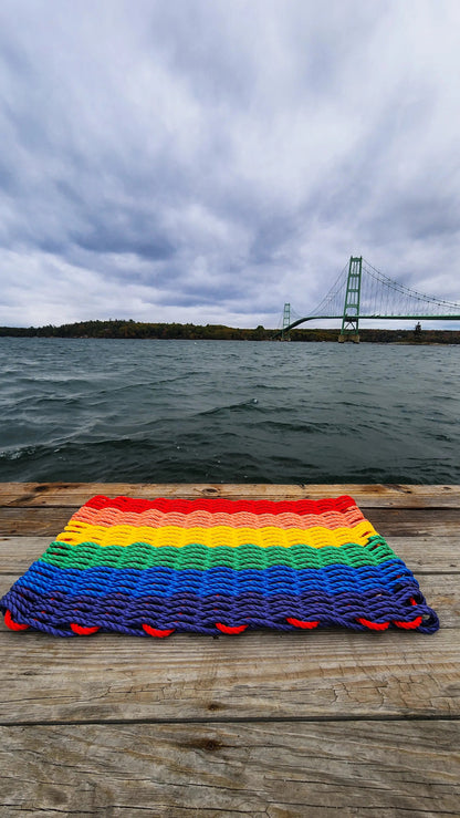 Colorful handmade rainbow rope welcome mat made from lobster rope, displayed on a wooden floor