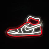 Neon light outline of a sneaker with bright red and white tubes, showing the shoe's sole, upper, and swoosh logo in a side view against a black background.