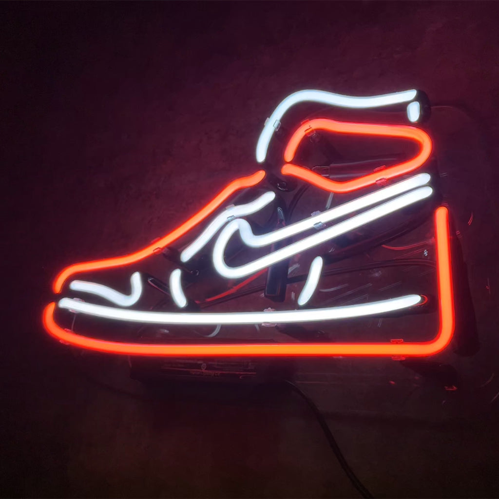 Neon sign shaped like a sneaker outlined in bright red and white light on a dark background.