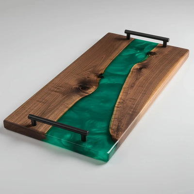 Handcrafted charcuterie board made from live edge black walnut wood with a glossy emerald green resin river running through the center, featuring matte black metal handles.