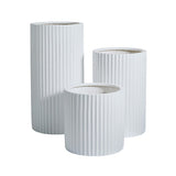 Three white cylindrical planters with vertical ribbed textures in varying heights and diameters against a white background.