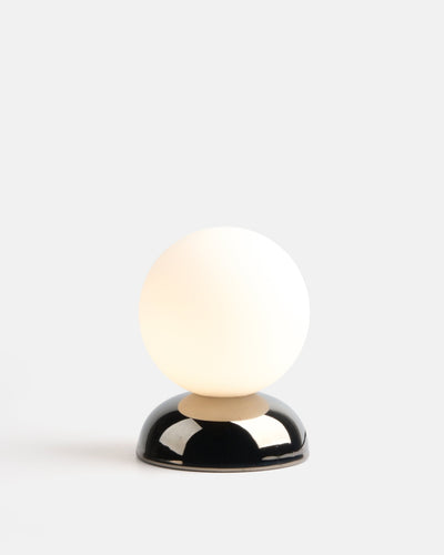 Ripple I Table Lamp with polished chrome glaze, stoneware base and 5-inch glass globe resting on a wooden surface.