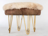 Round pouf bench with a plush cream sheepskin cushion top and brown suede sides, supported by six decorative gold metal hairpin legs with looped accents.