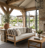 Neutral-toned sofa with striped and solid Shoreline Pillow Covers in pebble on a covered patio featuring wood beams, a stone fireplace, and open glass doors to a backyard.