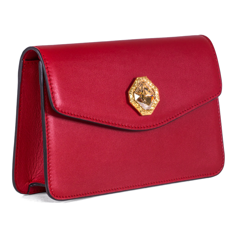 Red leather clutch bag with gold chain and central Swarovski crystal stone on a neutral background
