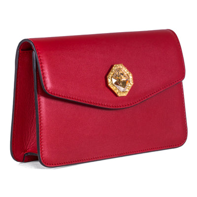 Red leather clutch bag with gold chain and central Swarovski crystal stone on a neutral background