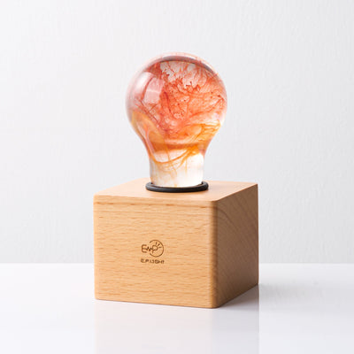 Handcrafted sunflower-shaped resin LED light bulb glowing warmly on a dark background