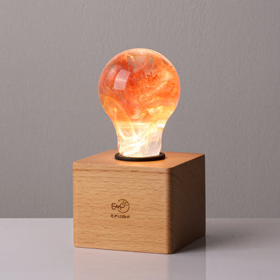 Handcrafted sunflower-shaped resin LED light bulb glowing warmly on a dark background