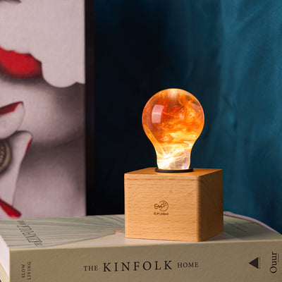 Handcrafted sunflower-shaped resin LED light bulb glowing warmly on a dark background
