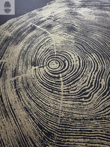 Close-up of gold tree rings pattern on black background, resembling the cross-section of a redwood trunk with distinctive concentric growth rings and textured lines.