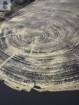 Close-up of redwood tree rings in gold against a black background, showing detailed concentric growth patterns and natural textures.