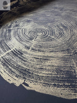 Close-up of a circular redwood cross section with gold-colored growth rings and black spaces accentuating the wood grain texture on a dark background.