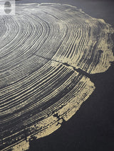 Close-up of gold leaf wood grain pattern on black background, highlighting concentric growth rings and natural wood texture in artistic detail.
