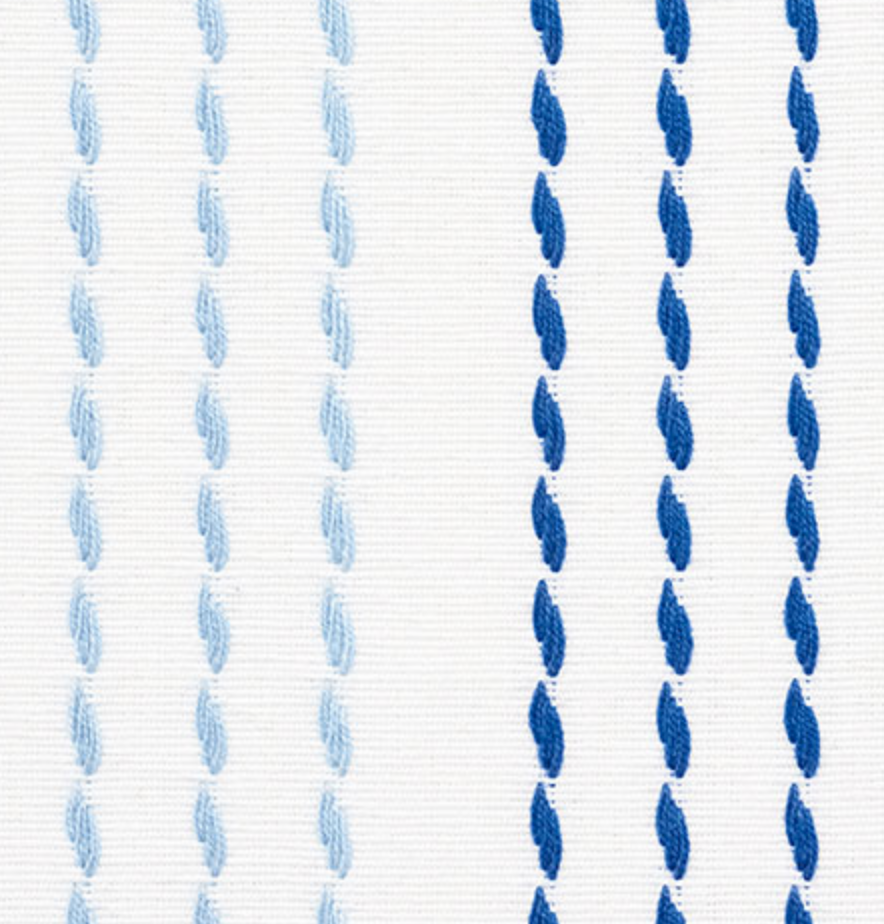 Close-up of white fabric with vertical running stitch embroidery in alternating light and dark blue threads.