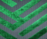 Close-up of emerald green cut velvet geometric pattern on dark gray fabric, showing soft texture and raised rectangular shapes in a repetitive linear design.