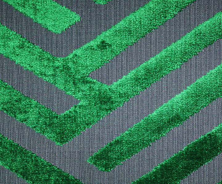 Close-up of emerald green cut velvet geometric pattern on dark gray fabric, showing soft texture and raised rectangular shapes in a repetitive linear design.