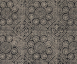 Close-up of a black fabric with a beige floral pattern made of small dots arranged in spirals and flower shapes.